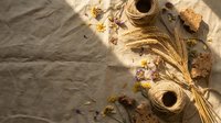 Rustic flat lay with natural jute twine, dried flowers and cork pieces on textured linen fabric background for crafting and DIY projects.