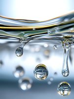 Macro shot of water surface with droplets and bubbles forming, showing liquid tension and reflective properties for science or environmental concepts.