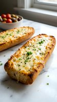 Two golden baked cheese boats with melted cheese and fresh herbs on marble counter, bowl of olives in background for Mediterranean cuisine content.