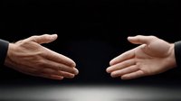 Two business hands reaching toward each other for handshake against dark background symbolizing partnership, agreement, cooperation and professional meeting.