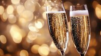 Two elegant champagne flutes filled with sparkling golden champagne against warm bokeh lights background for celebration and luxury events.