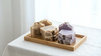 Handmade natural soap bars with dried flowers on wooden tray, organic skincare products for spa and wellness routines.