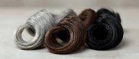 Three coiled bundles of natural fiber rope or twine in gray, brown and black colors arranged on neutral background for crafting projects.