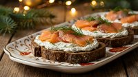 Smoked salmon canapes with cream cheese and dill on dark bread served on elegant plate with festive lighting for holiday entertaining and appetizers.