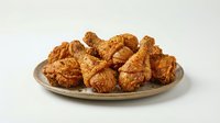 Crispy fried chicken pieces with golden-brown coating arranged on ceramic plate against white background, ready for food photography and restaurant menu use.