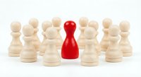 Red pawn piece standing out among wooden chess pawns, symbolizing leadership, individuality, and uniqueness in business and team concepts.