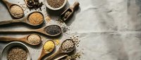 Assorted organic seeds and grains in wooden spoons and bowls on rustic background. Healthy superfood ingredients for cooking and nutrition.
