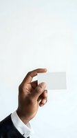 Male hand with dark skin tone holding blank white business card against neutral background. Professional businessman displaying empty card for branding and corporate identity design.
