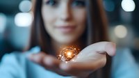 Young woman holding glowing magical light sphere in palm against blurred background with bokeh lights, concept of spirituality and mystical energy.