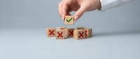 Business person selecting green checkmark cube from red X mark blocks representing positive choice and decision making in corporate strategy.