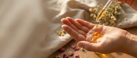 Woman hands receiving golden healing oil drops from dropper bottle for aromatherapy wellness spa treatment and natural skincare routine.