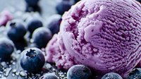 Creamy blueberry ice cream scoop with fresh berries and dark chocolate crumbs scattered around, showcasing rich purple color and smooth texture for food photography.