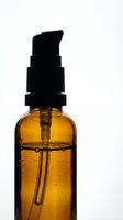 Amber glass bottle with black pump dispenser containing golden liquid, isolated on white background for skincare, cosmetics, essential oils, serums, and beauty product packaging design.