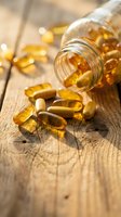 Golden vitamin capsules spilling from glass bottle onto rustic wooden surface with warm natural lighting for health and wellness concepts.