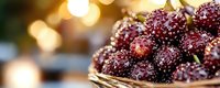 Ripe dark berries with dewdrops in woven basket, golden sunlight bokeh background. Fresh produce, farmers market, organic fruit harvest, food photography for culinary, wellness, and agriculture content.
