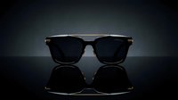Stylish black sunglasses with gold accents on reflective surface against dark gradient background for luxury fashion and eyewear advertising campaigns.