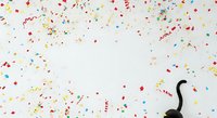 Colorful confetti and streamers scattered on white background with black party horn, isolated design element for celebrations, events, and festive occasions.