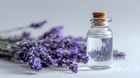 Lavender essential oil in glass bottle with cork stopper and fresh purple lavender flowers on light background for aromatherapy and spa treatments.