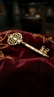 Ornate golden vintage key with decorative scrollwork resting on luxurious burgundy velvet fabric with gold embroidered trim against blurred dark background.
