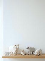Minimalist wooden sheep figurines arranged on shelf with neutral tones, featuring grazing and standing poses for home decor and interior styling.
