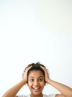 Excited young woman with dark curly hair touching head, wearing white shirt, expressing joy and surprise against isolated white background for advertising and lifestyle content.