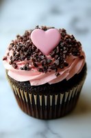 Chocolate cupcake with pink frosting and heart decoration topped with chocolate crumbs for Valentine's Day celebration and romantic dessert occasions.