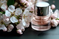 Luxury cosmetic bottle with spring cherry blossoms on dark background, soft focus close-up of pink glass container and delicate white petals.