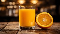 Fresh orange juice in glass with sliced orange half on rustic wooden table. Healthy breakfast drink with vitamin C for morning nutrition and wellness lifestyle.
