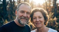 Happy mature Caucasian couple smiling outdoors in golden sunlight with trees in background for lifestyle and relationship content.