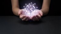 Hands holding glowing digital network sphere with connected nodes and light effects representing global connectivity and technology innovation.