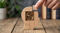 Human head profile made of wooden blocks with gear mechanism inside representing cognitive processes and mental development on rustic table.