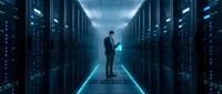 Professional businessman working with tablet in modern data center server room with blue lighting and network infrastructure for technology solutions.