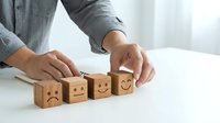 Business professional arranging wooden emotion blocks from sad to happy face showing customer satisfaction rating and feedback concept.