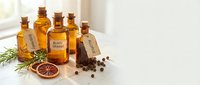 Amber glass bottles with essential oils, spices and herbs on neutral background. Natural aromatherapy ingredients for wellness and spa treatments.