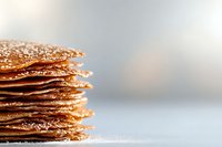 Stack of golden crispy crepes dusted with powdered sugar, perfect for breakfast, dessert, or bakery marketing materials.