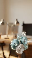 Transparent glass gears floating in modern office workspace representing teamwork, innovation and business process automation in corporate environment.