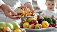 Fresh colorful fruits and vegetables on white serving plate with hands holding healthy meal, bright natural food photography for restaurant menu.