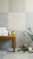 Serene spa bathroom with wooden bench, stacked white towels, bath oils, eucalyptus branch, zen stones, and candle against stone tiles.