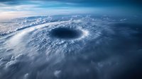 Aerial view of massive hurricane eye formation with swirling clouds and dramatic atmosphere seen from space, showing powerful weather system over ocean surface.