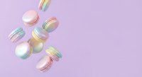 Colorful macarons falling on pastel purple background. French pastry dessert cookies in motion for bakery, cafe menu, food blog design.