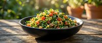 Colorful tabbouleh salad with fresh herbs, vegetables and grains served in black bowl outdoors for healthy eating and Mediterranean cuisine.