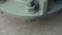 Industrial machinery component with bolt and nut assembly on green metal surface for manufacturing and engineering applications.
