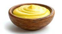 Bright yellow mustard sauce in wooden bowl isolated on white background, ready for gourmet food presentation or condiment serving.