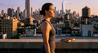 Young woman practicing yoga meditation on urban rooftop at sunset with city skyline background. Peaceful mindfulness exercise outdoors for wellness and relaxation.