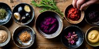 Vibrant homemade sauces, dips and condiments in rustic ceramic bowls on wooden table. Fresh herbs and spices add gourmet flavor to colorful spreads.