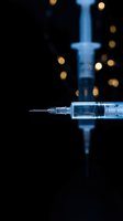 Medical syringe with needle on dark background with bokeh lights for healthcare and vaccination concepts.