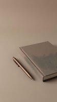 Minimalist workspace with elegant copper pen and neutral hardcover notebook on warm beige background for professional branding and stationery design.