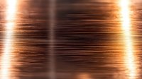 Glowing copper metallic texture with horizontal light streaks and reflective surface creates dramatic industrial background effect for luxury designs.