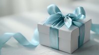 Elegant white gift box with shiny teal blue satin ribbon and bow on light wooden surface, perfect for celebrations, holidays, and special occasions.