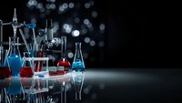 Laboratory glassware with colorful chemical solutions on reflective surface against dark background with bokeh lights for scientific research.